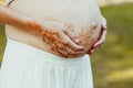 Graceful hands with mehendi hold painted pregnant belly Royalty Free Stock Photo