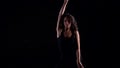 Graceful lady is dancing alone in darkness, wriggling her slender body in black background