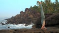 Lady in grey does yogic headstand on flat rock slow motion