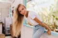 Graceful lovely woman with long hairstyle posing near window. Adorable fair-haired girl sitting on