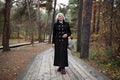 Graceful mature woman dressed in chic black coat, stroll through enchanting forest, reveling in splendor of nature with