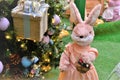 Stuffed bunny in a salmon dress carrying basket of flowers in Christmas decoration