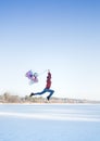 graceful slender pretty teenage girl  holding many colorful balloons in her hands  jumping over the snowy ground Royalty Free Stock Photo