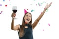 Graceful, smiling young brunette girl in party hat with glass of red wine dancing under confetti and laughing, white Royalty Free Stock Photo