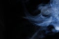 Graceful swirls of blue smoke isolated from black background. Close-up of vapor. Soft focus and texture from vintage lens.