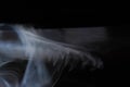 Graceful swirls of white smoke from black background. Close-up of vapor. Soft focus and texture from vintage Helios lens.