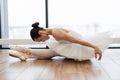 Graceful woman ballet dancer stretching while sitting on wooden floor. Royalty Free Stock Photo
