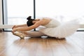 Graceful woman ballet dancer stretching while sitting on wooden floor. Royalty Free Stock Photo