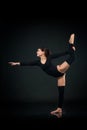 graceful woman gymnast standing in splits against dark background Royalty Free Stock Photo