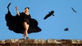Graceful young girl in a flying black dress and shorts against the blue sky and flying eagles. Royalty Free Stock Photo