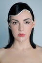 Graceful young woman with pearl beads on face. Female fashion portrait. Creative evening makeup with decorative details.