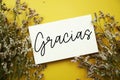 Gracias (Spanish language) text with flowers decoration on yellow background Royalty Free Stock Photo