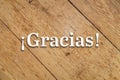 `Gracias` text on a wooden background. Translation: `Thanks`