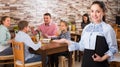 Gracious young waitress warmly welcoming guests to family cafe Royalty Free Stock Photo