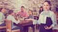 Gracious young waitress warmly welcoming guests to family cafe