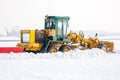 Grader clears snow on the taxiway at the airport