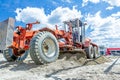 Grader is leveling ground at construction site, view on undercarriage