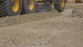 Grader machine leveling rubble stones on new road construction