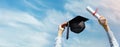 graduate with diploma and cap in hands on blue sky background celebrating college graduation. copy space