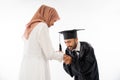 Graduate male student wearing toga shaking hands kissing mother's hand