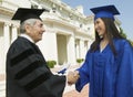 Graduate shaking hand of dean outside university