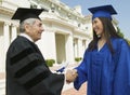 Graduate shaking hand of dean outside university side view