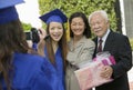 Graduate videotaping other graduate with mother and grandfather outside Royalty Free Stock Photo