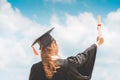 Graduated woman in cap and gown holding certificated celebrating in Commencement day with blue sky on the beach Royalty Free Stock Photo