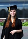 Graduate young girl with red hair dressed in mantle and square academic cap smile in university campus courtyard Royalty Free Stock Photo