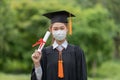 Graduated woman wear cap gown and Medical mask for protection virus holding diploma or certificated due Virus outbrake Royalty Free Stock Photo