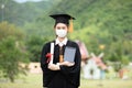 Graduated woman wear cap gown and Medical mask for protection virus holding diploma or certificated and tablet due Virus outbrake Royalty Free Stock Photo