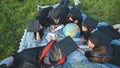 Graduates in black robes looking at a georgraphic globe lying on the grass.