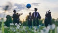 Graduates in costume playing with a ball at sunset. Royalty Free Stock Photo