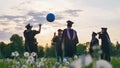 Graduates in costume playing with a ball at sunset. Royalty Free Stock Photo