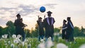 Graduates in costume playing with a ball at sunset. Royalty Free Stock Photo