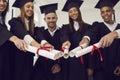 Graduates friends joining diplomas together as symbol of unity, common achievement, team, success Royalty Free Stock Photo