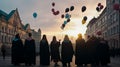 Graduates in robes caps launch balloons into sky after graduation. Silhouettes of students in light of sun's rays