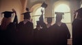 Graduates in robes and caps throw up their hats after graduation. Ceremony is tradition of graduation. Silhouettes Royalty Free Stock Photo