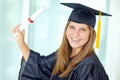 Graduating with flying colours. A pretty college student in her graduation gown holding her degree and smiling happily. Royalty Free Stock Photo