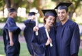 Graduating together. Portrait of a smiling graduate couple holding their diploma with her former graduates in the Royalty Free Stock Photo