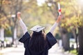 Graduation, back and woman student celebrating academic success or raising her diploma or victory at university campus