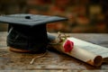 Graduation cap and diploma with red ribbon on wooden table with bokeh lights background Royalty Free Stock Photo
