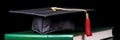 Graduation cap and diploma scroll on books with dark minimalist background Royalty Free Stock Photo