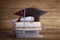 Graduation cap with graduation paper on a stack of book