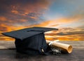 graduation cap, hat with degree paper on wood table, sunset sky