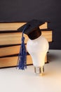 Graduation cap on light bulb with books close-up. Education idea. Vertical image Royalty Free Stock Photo