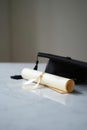 Graduation cap and rolled diploma on marble table with soft studio lighting Royalty Free Stock Photo