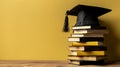 Graduation cap on a stack of books on a bright yellow backgdrop with empty space Royalty Free Stock Photo