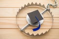 Graduation cap in a trap on wooden table background. College or university degrees are not important in future, education loan