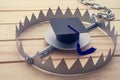Graduation cap in a trap on wooden table background. College or university degrees are not important in future, education loan